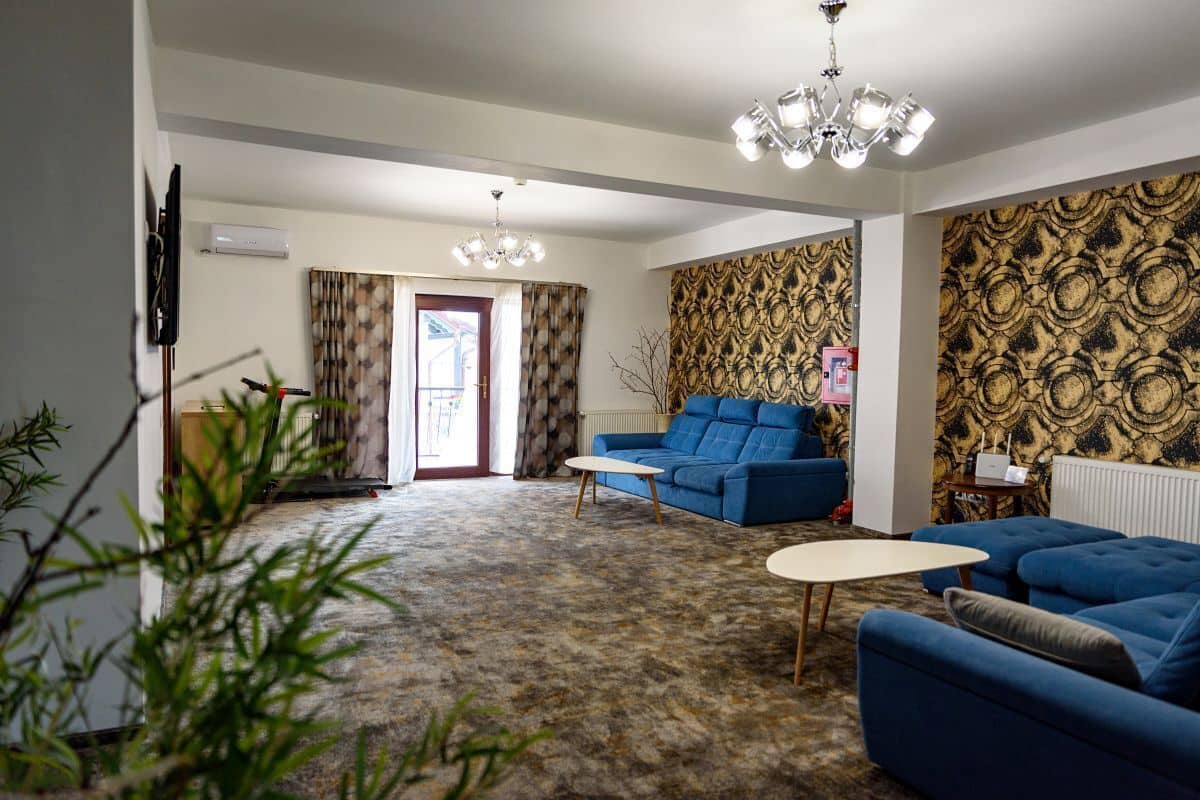 A living room with a blue sofa, a coffee table, and a patterned wall.