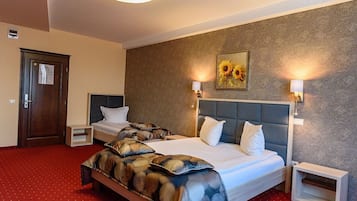 Een hotelkamer met twee bedden, een rood tapijt, een houten deur en een schilderij aan de muur.