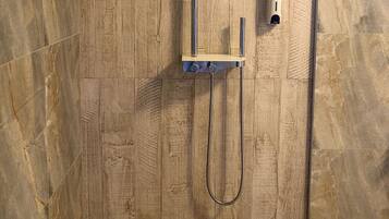 Une douche équipée d’un pommeau de douche à main et d’un panneau de commande fixé au mur.
