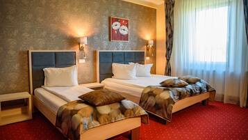 A hotel room with two beds, a red carpet, and a wall with a floral painting.