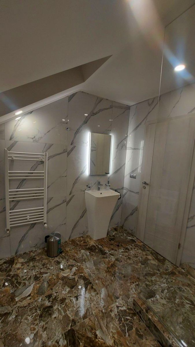 A bathroom with a marble floor, a sink, a mirror, and a towel rack.