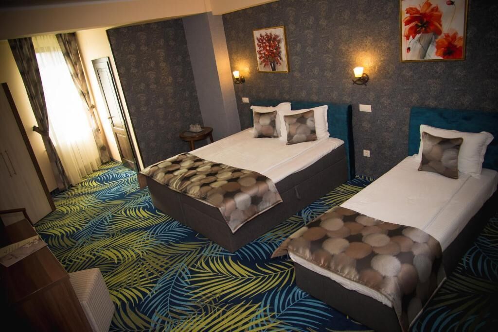 Quarto de hotel com duas camas, carpete estampado e luminárias fixadas na parede.