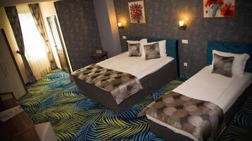 Quarto de hotel com duas camas, carpete estampado e luminárias fixadas na parede.