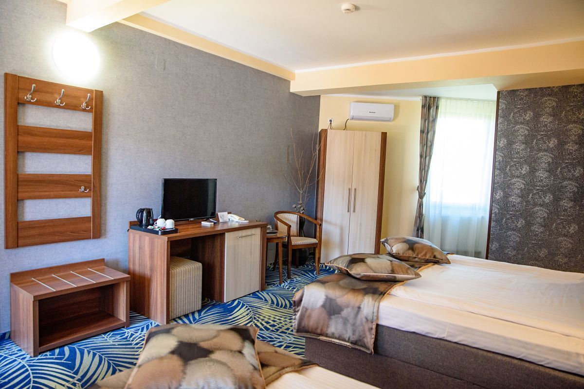 Ett hotellrum med en säng, ett skrivbord med en tv, en garderob och en sittgrupp.