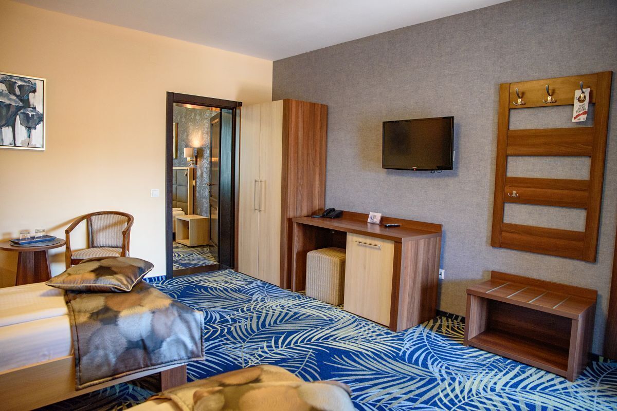Una camera d'albergo con un letto, una scrivania, una sedia, una televisione e un armadio.