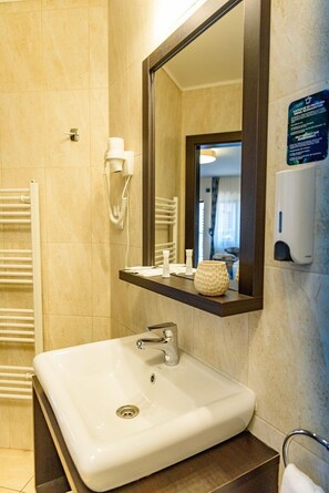 A bathroom with a white sink, a mirror, a towel rack, a phone, and a soap dispenser. - Hotel Stefani (Sibiu)