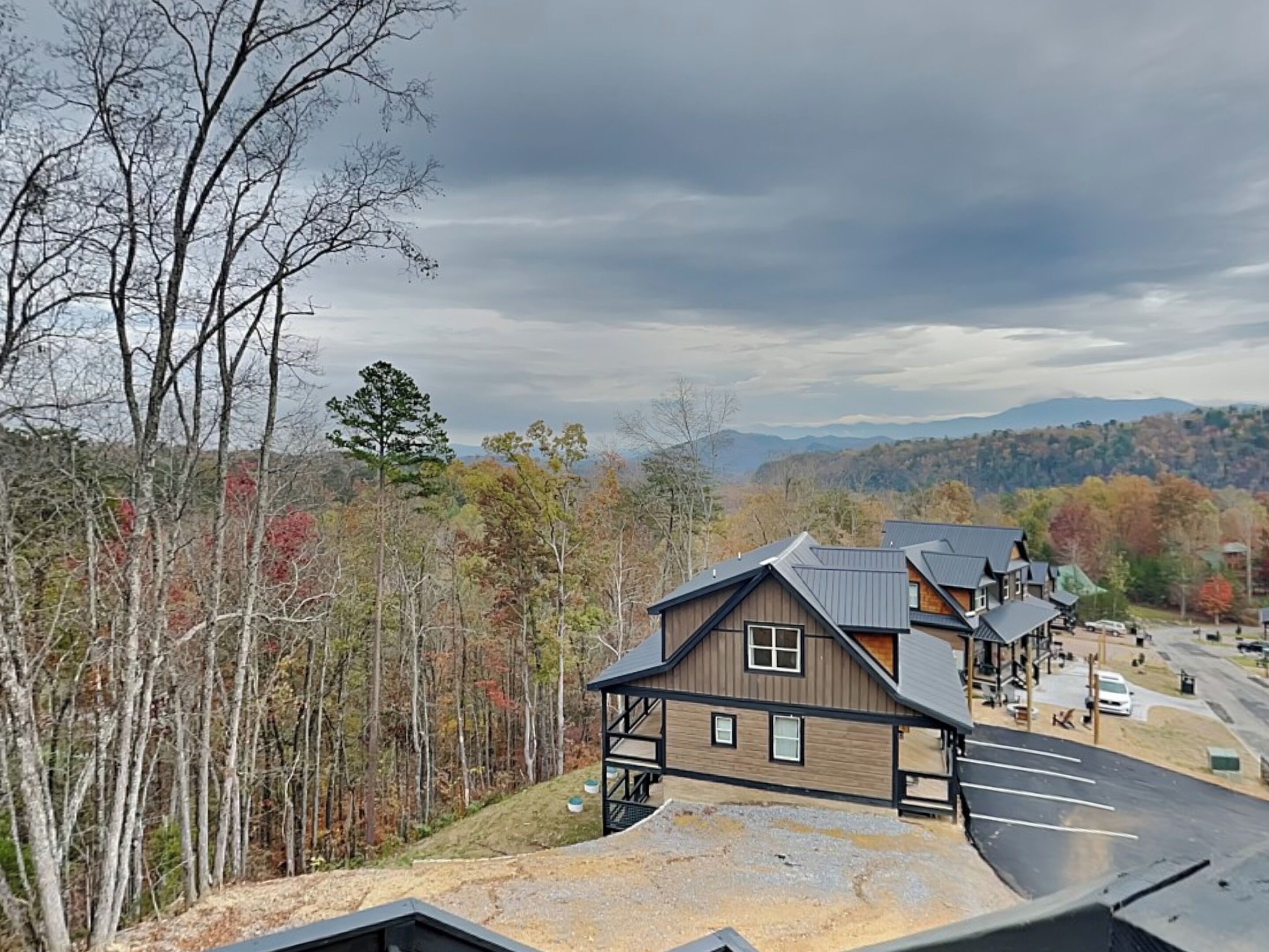 Un chalet doté d’un grand parking, de plusieurs bâtiments et entouré d’une forêt.