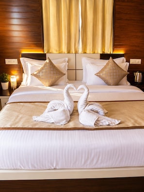 A hotel room with a large bed, two pillows, a bedside table with a lamp, and a wall socket. - The Udaisarovar - Lakeside Paradise (Udaipur)