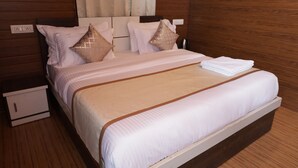 A neatly made bed with a white and brown bedspread, two pillows, and a folded white towel on the side. - The Udaisarovar - Lakeside Paradise (Udaipur)