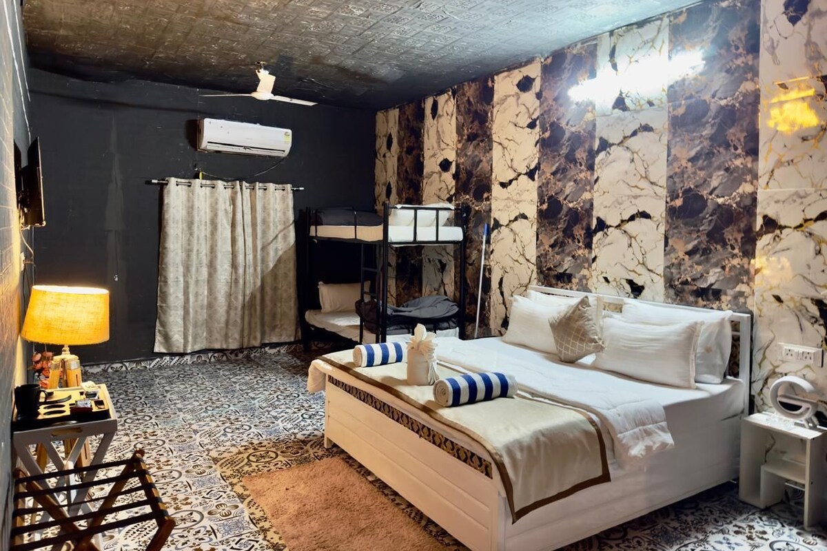 A hotel room with a bed, a bedside table, a lamp, a ceiling fan, and a wall with a marble-like pattern.