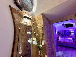 A corner of a room with a stone wall, a mirror, and a vase with white flowers. - Window in the Stone Naples (Naples)