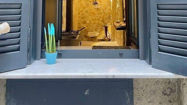 A doorway leading to a room with a stone wall and a small sink. - Window in the Stone Naples (Naples)