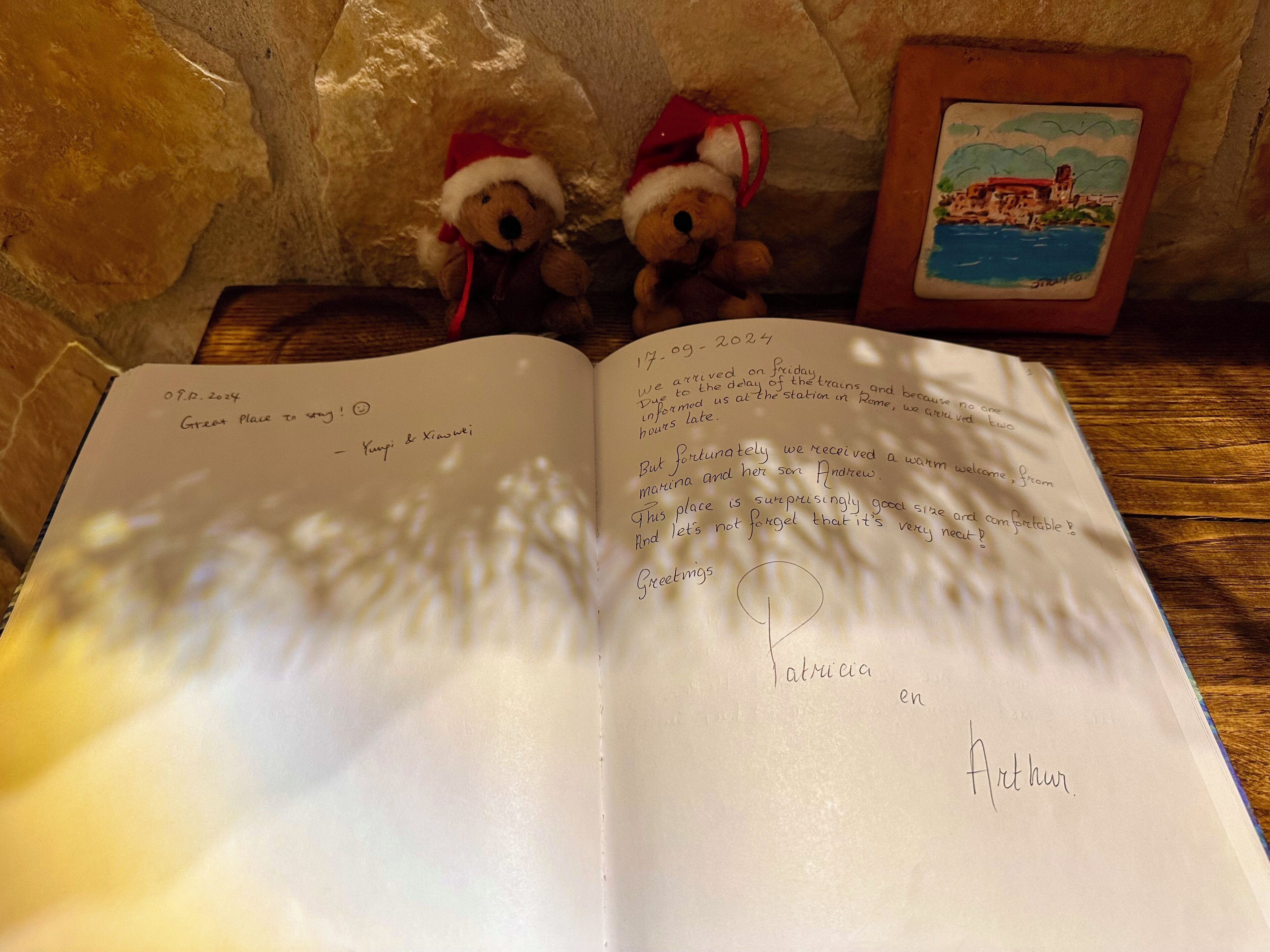 An open book with handwritten notes and two teddy bears wearing Santa hats.