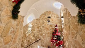 A stone-walled interior with a Christmas tree, a staircase, and signs indicating a café and brasserie. - Window in the Stone Naples (Naples)