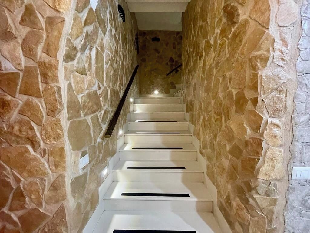 A staircase with white steps and stone walls.