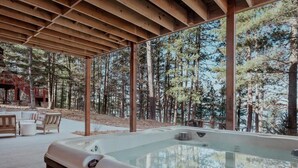 Un jacuzzi bajo una pérgola de madera con vistas al bosque.