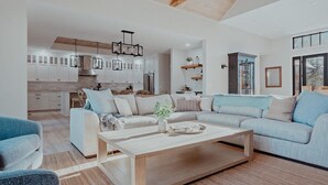 Una sala de estar moderna con un sofá, una mesa de centro y una cocina al fondo.
