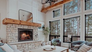 Una sala de estar acogedora con chimenea de piedra, ventanas amplias y asientos cómodos.