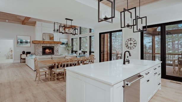 Una cocina moderna con una isla central, iluminación colgante y una chimenea.