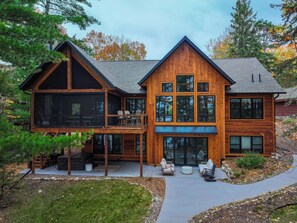 A two-story wooden house with a balcony and outdoor seating area. - Trout Lake, WFC |Swimming| Hot Tub| Kayaks (Crosslake)