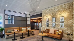 Een moderne lobby met een bakstenen muur, een zithoek en een receptiebalie.
