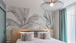 Een moderne hotelkamer met een groot bed, een hoofdbord met een houten afwerking en een muurschildering van palmbladeren.
