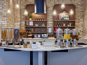 A breakfast bar with granola, cereal, and coffee options, a coffee machine, and a menu board. - Aparthotel Adagio London City East (London)