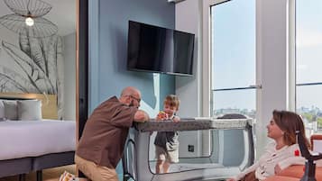 Ein modernes Wohnzimmer mit großem Fenster, Flachbildfernseher und einer Couch.