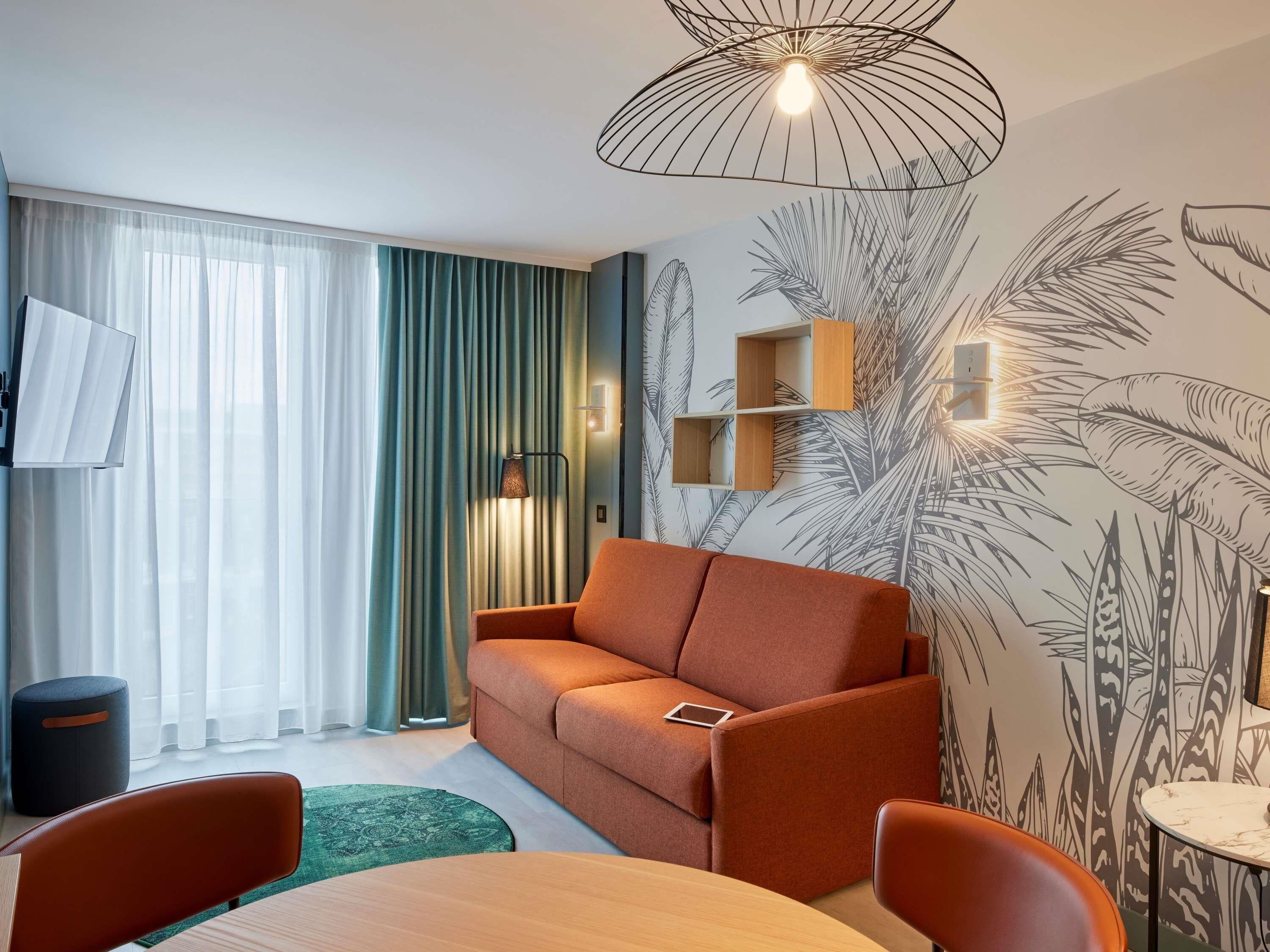 Una sala de estar moderna con un sofá, una mesa de comedor y un televisor montado en la pared.