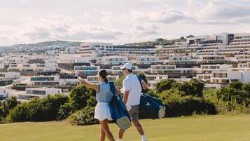 A couple on a golf course with modern buildings in the background.
