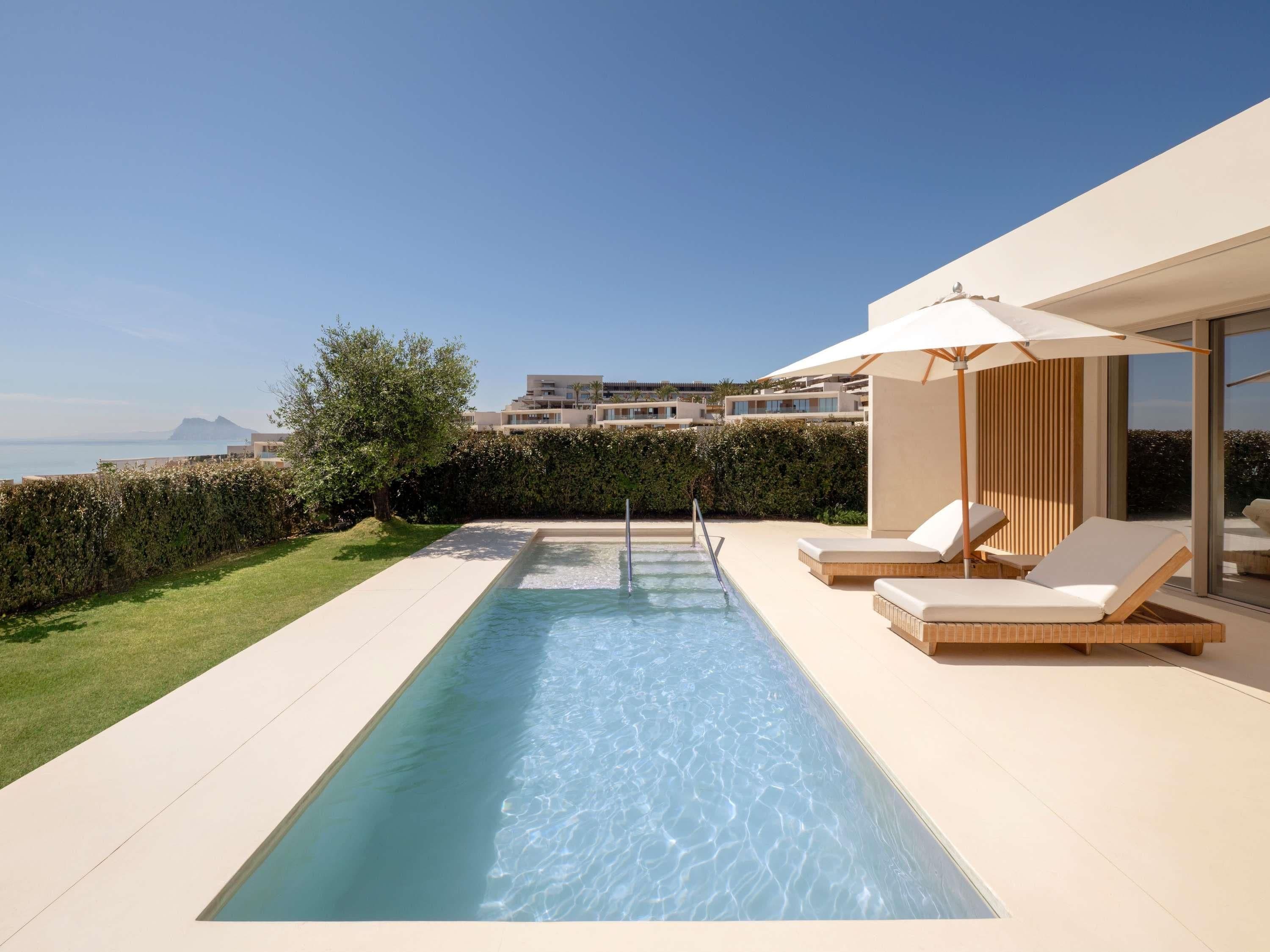 Una piscina con sillas de descanso y vistas al mar.