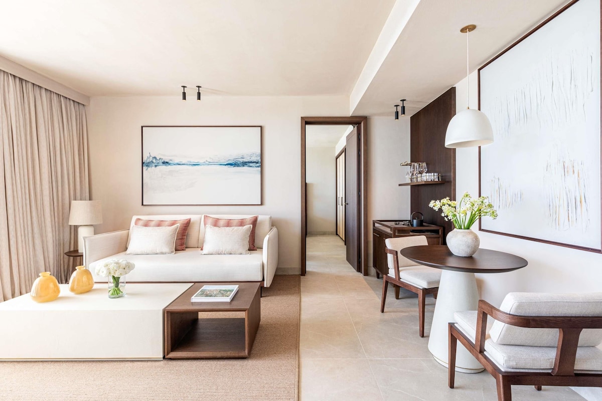 Une chambre d’hôtel moderne équipée d’un canapé, d’une table basse, d’une table à manger et d’œuvres d’art.