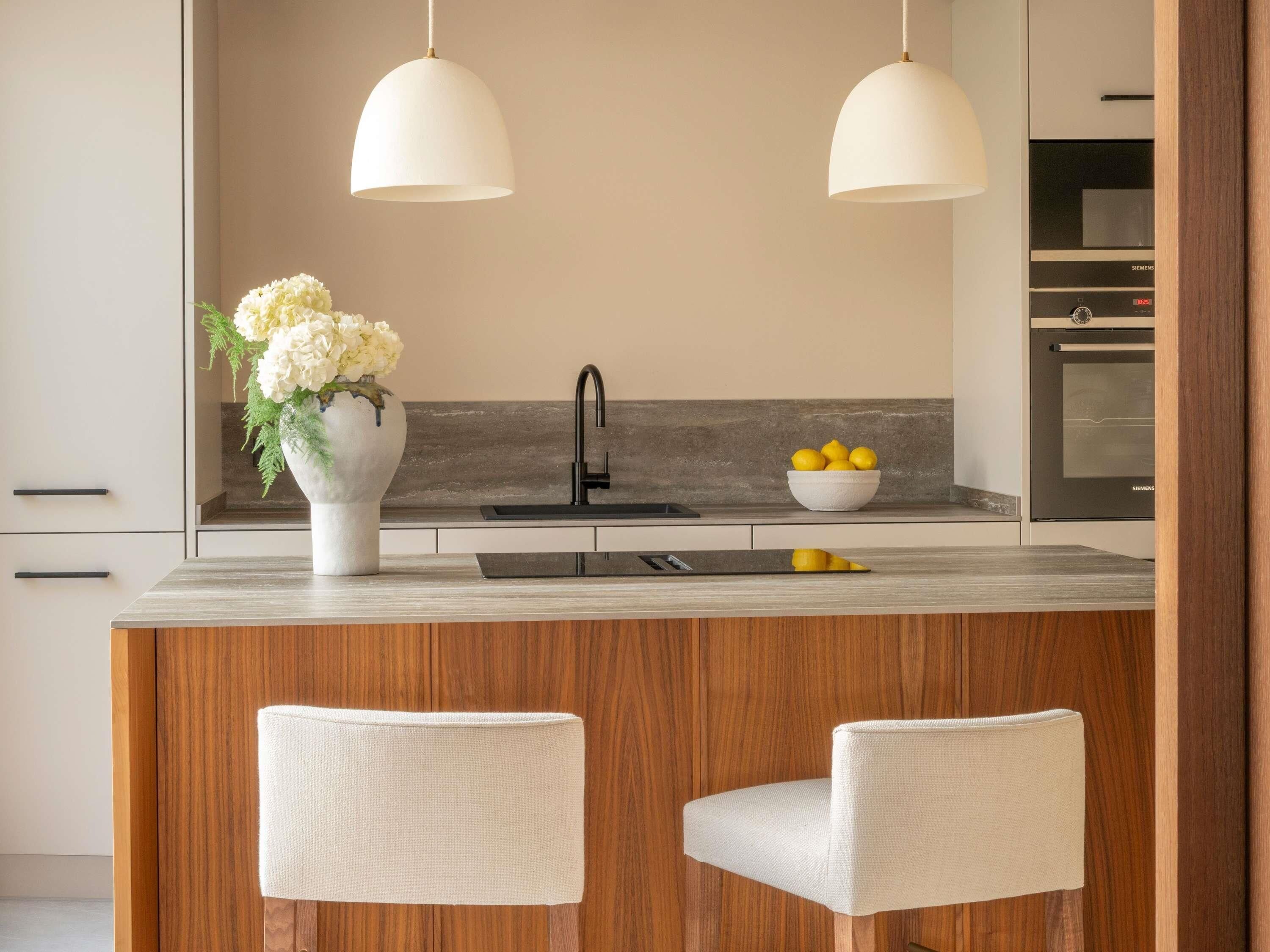 A modern kitchen with a central island, two pendant lights, a sink, and a Siemens oven.