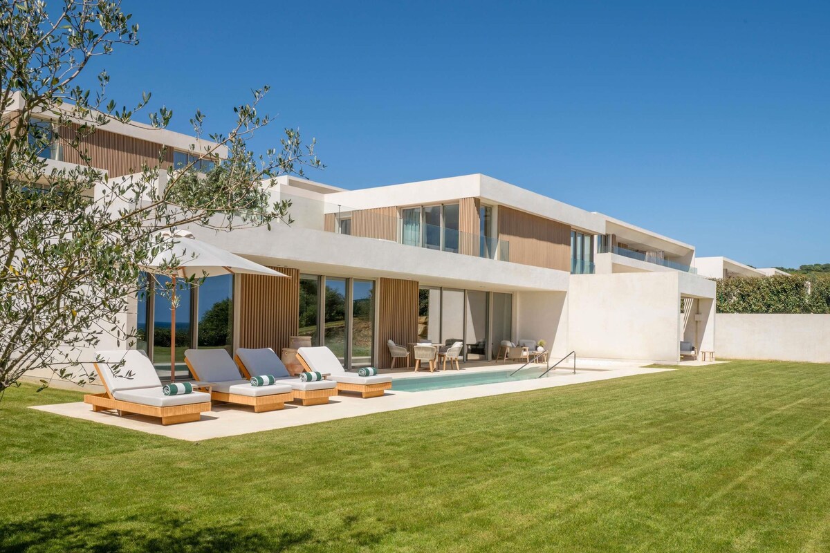 Une maison moderne à deux étages, dotée d’une piscine, d’un espace salon extérieur et d’une pelouse bien entretenue.