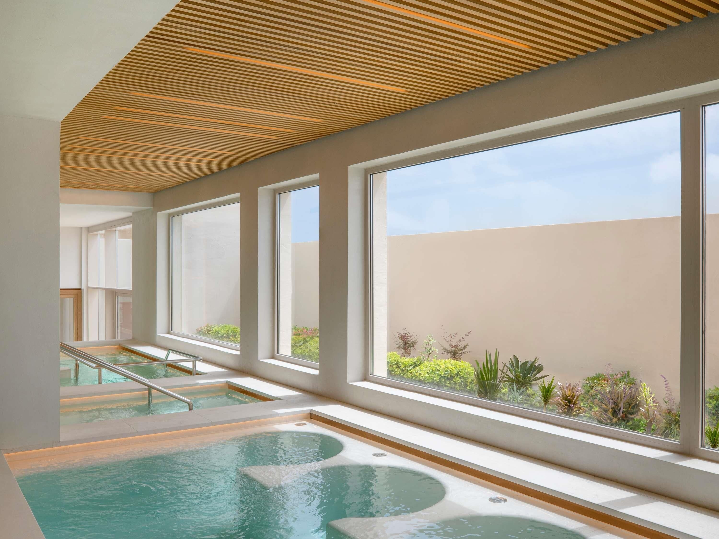 A spa area with a pool, large windows, and a wooden ceiling.