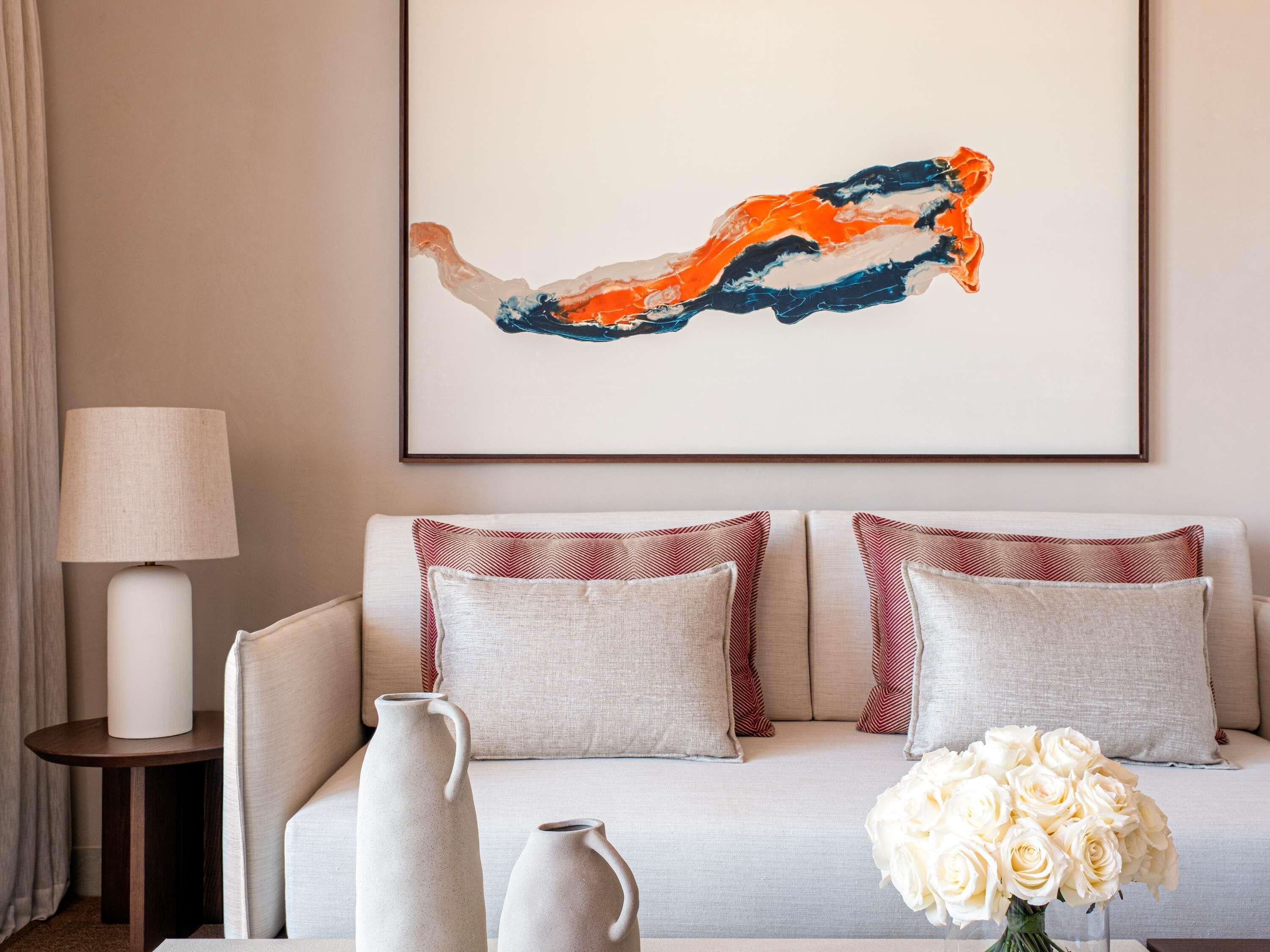 Un salon avec un canapé, deux vases et un tableau abstrait encadré.