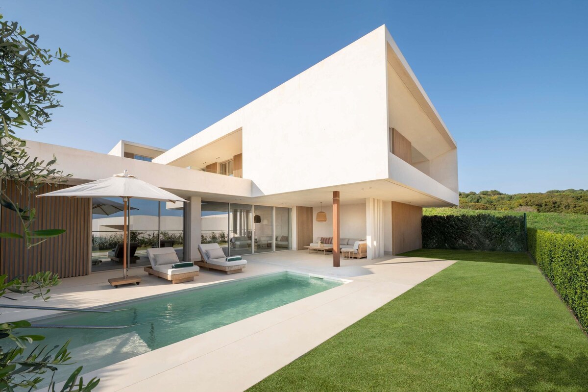 Une maison moderne dotée d’une piscine, d’un espace salon extérieur et d’une pelouse bien entretenue.