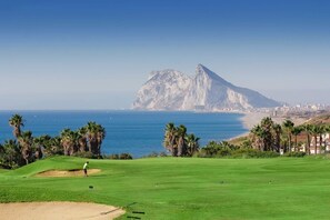 A golf course with a view of a coastal city and a prominent mountain in the background. - Fairmont La Hacienda Costa del Sol (San Roque)