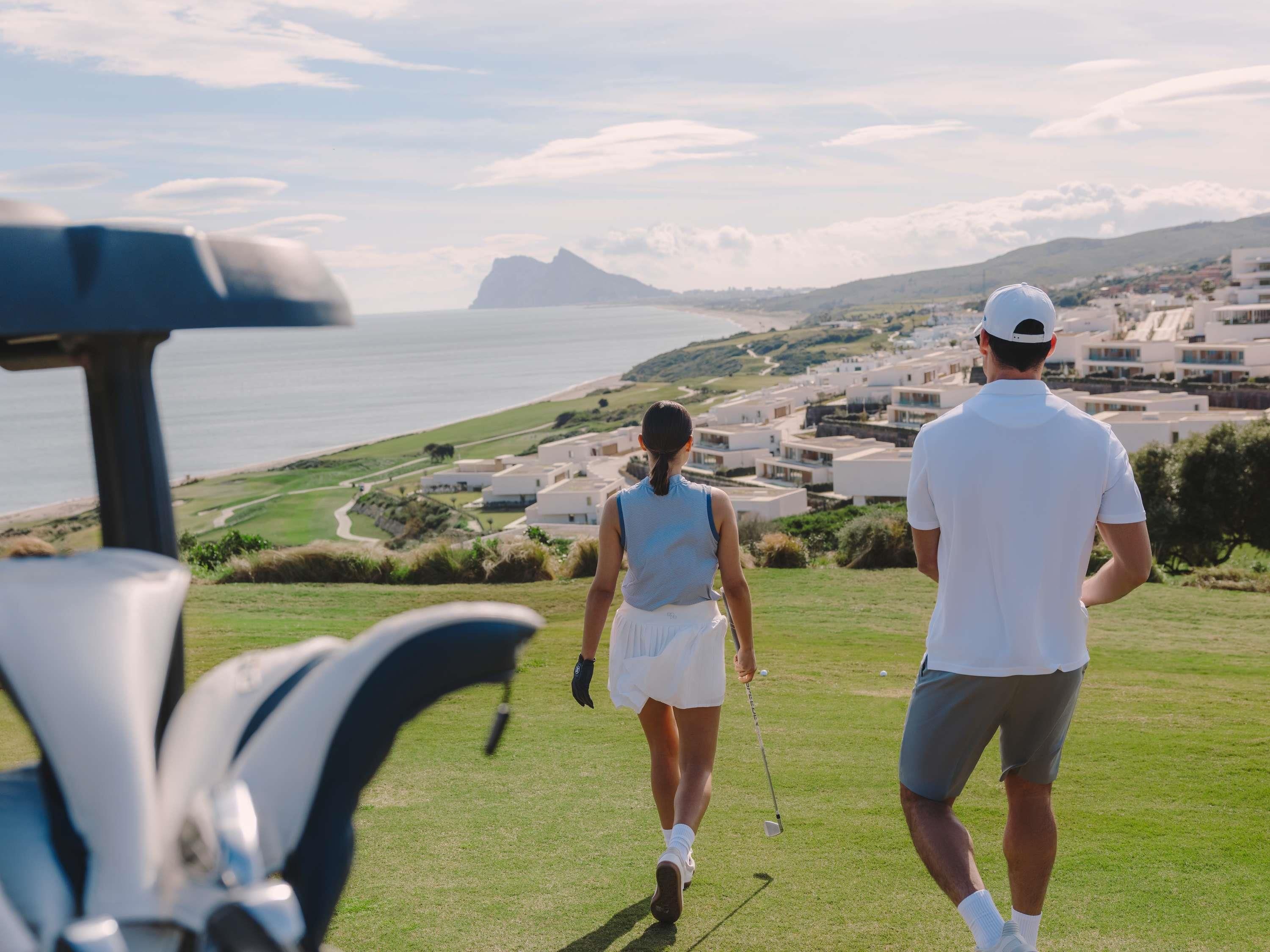 A golf course with a view of the ocean and a town in the background.