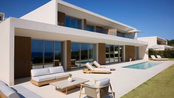Une maison moderne à deux étages dotée d’un grand balcon en verre, d’un espace salon extérieur et d’une piscine.