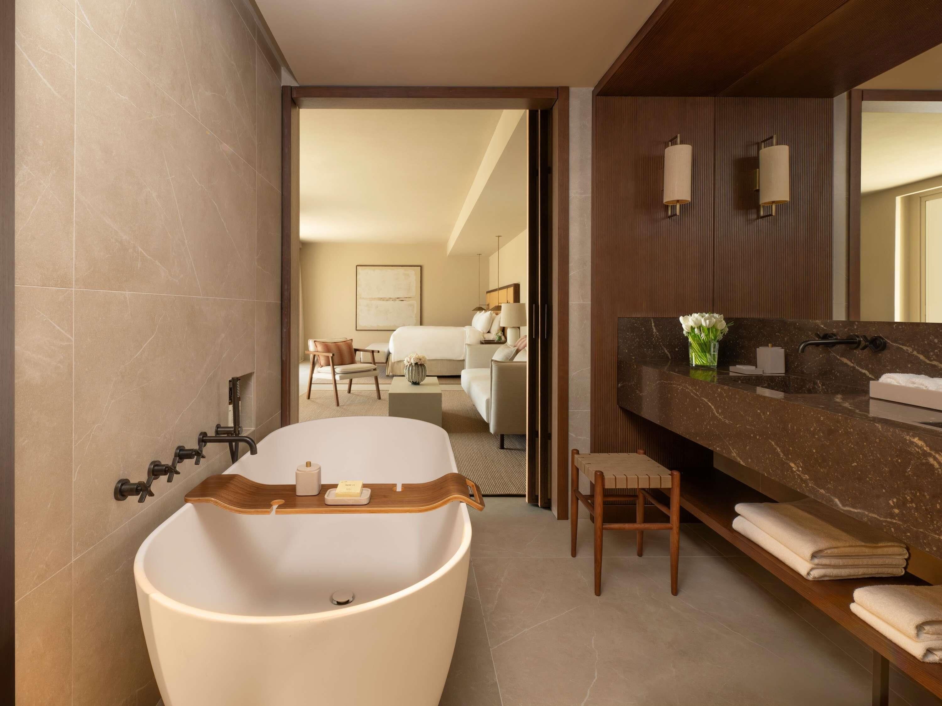 A modern bathroom with a freestanding bathtub, a wooden vanity, and a large mirror.