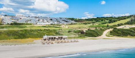 A coastal resort with beachfront villas, a golf course, and a beach area.