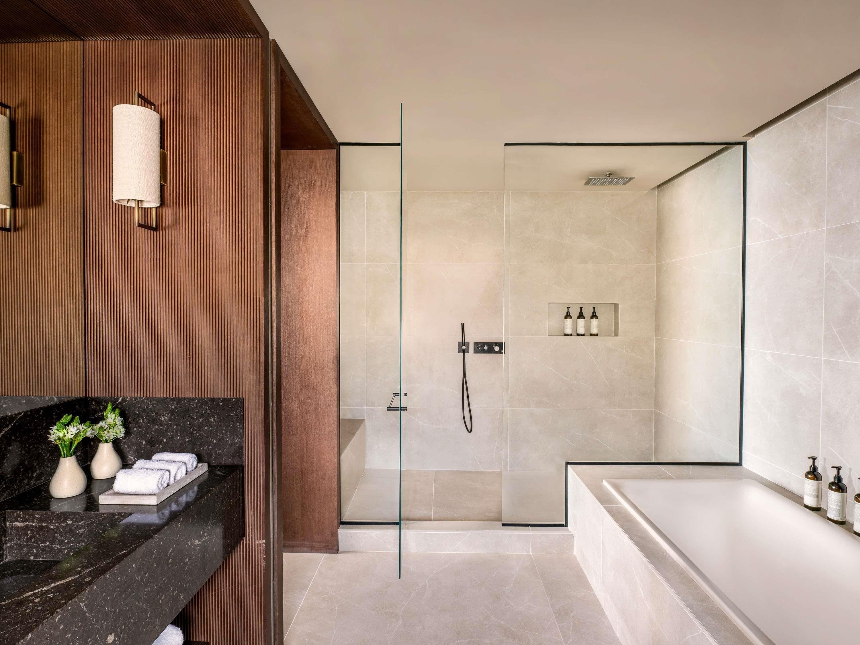 A modern bathroom with a glass-enclosed shower, a marble countertop, and a large bathtub.