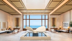 A spacious lobby with a large window overlooking the sea, a central seating area, and a modern design with wooden paneling and a high ceiling. - Fairmont La Hacienda Costa del Sol (San Roque)