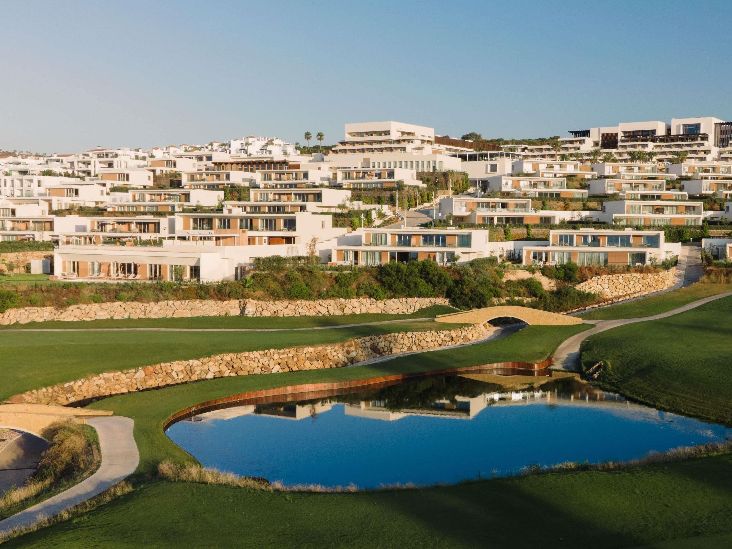 Un área residencial moderna con arquitectura contemporánea, un césped cuidado y una pequeña laguna.