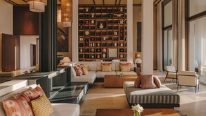 Un vaste espace de vie comprenant un grand canapé, une table basse et une bibliothèque remplie d’objets décoratifs.