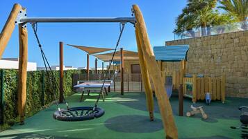 Un parque infantil con columpios, un tobogán y una mesa de tenis.