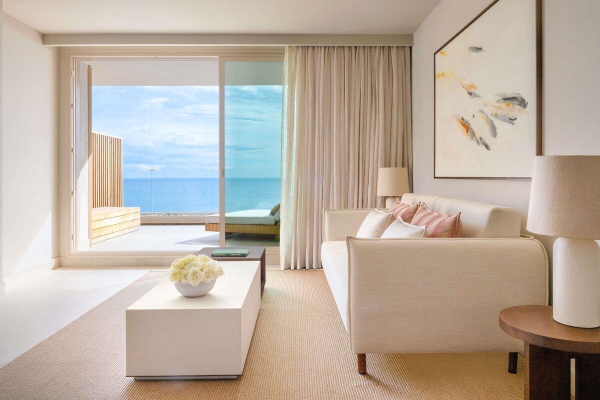 Une chambre d’hôtel moderne avec un balcon, un canapé, une table basse et un tableau.