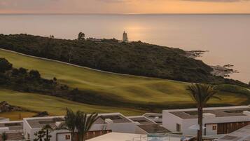 A resort with a swimming pool, lounge chairs, and a view of the sea.