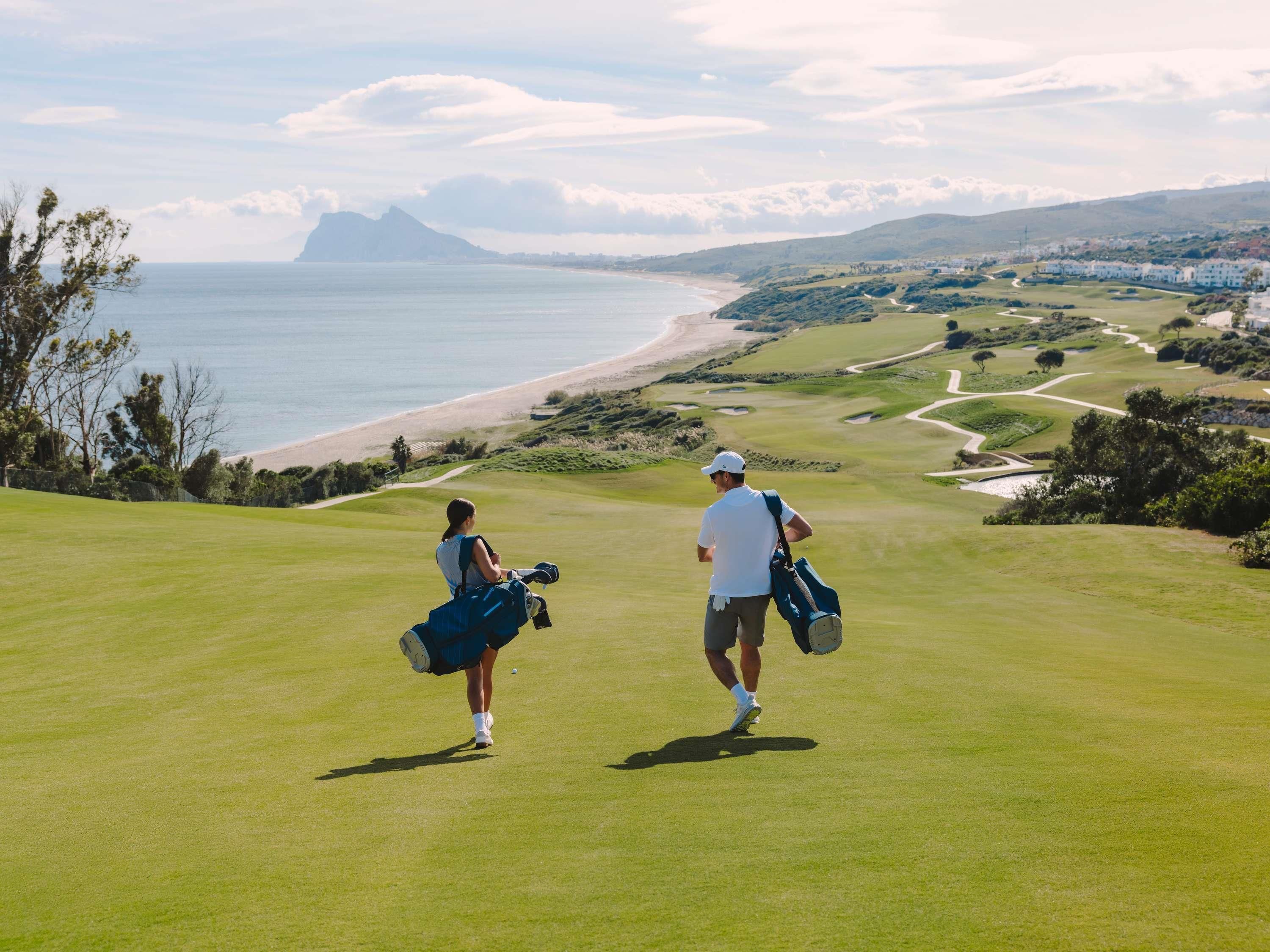 Un campo de golf con vistas al océano y colinas al fondo.